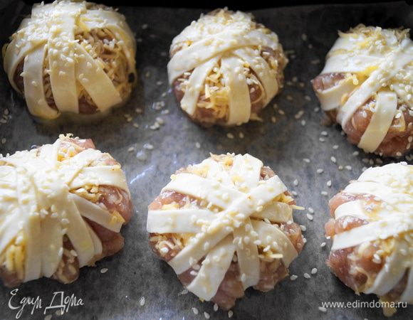 Обмотать слоеными полосками наши мясные шарики, так как будто наматываете нитки на клубок. Выложить на противень, смазать взбитым желтком и посыпать кунжутом. Поставить в разогретую до 180 градусов духовку. Выпекать до золотистой корочки. 