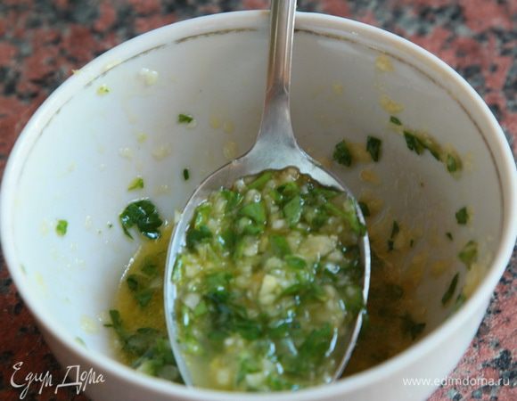 Пока пампушки выпекаются, готовим заливку: мелко нарезаем чеснок и петрушку, добавляем масло и растираем в плошке. Затем добавляем 2 столовые ложки воды и хорошо перемешиваем. Получается такая густенькая смесь.