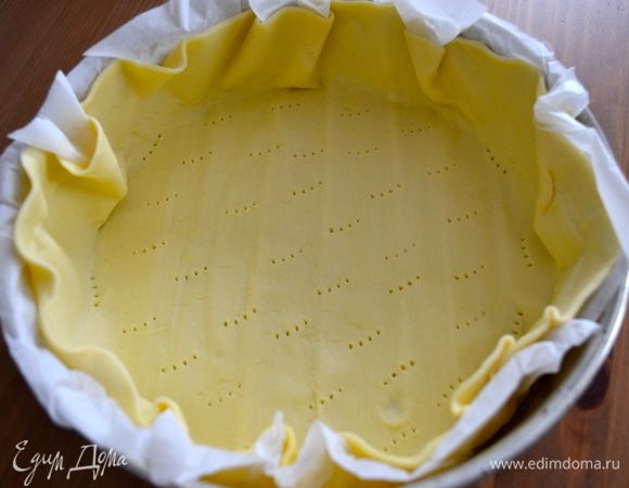 Переходим к основанию флана. Для этого возьмите пласт готового слоеного теста (или домашнего), выложите его форму диаметром 24 см (если используете готовое тесто, то вместе с пекарской бумагой, используя свое слоеное тесто, смажьте форму маслом и присыпьте мукой). Сформируйте достаточно высокий бортик, так как крема будет много! Наколите тесто вилкой, чтобы оно не вздувалось при выпечке.