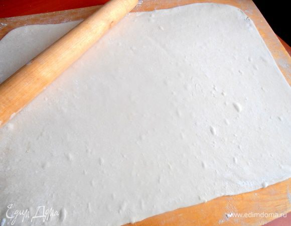 Размораживаем и раскатываем прямоугольником тесто, припорошив доску мукой...