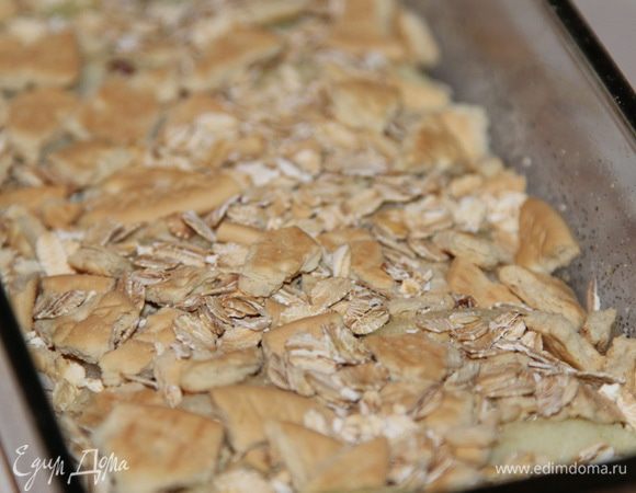 Следующим слоем снова крошим галетное печенье и добавляем еще овсяные хлопья не быстрого приготовления: