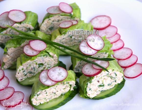 Для подачи нарезаем по диагонали огурец, выкладываем на блюдо. На каждый кусочек огурца кладём нарезанный кусочками рулет. Украшаем редисом и перьями лука.