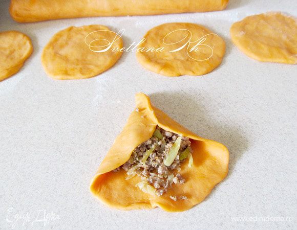 Тесто разделить на 2 части для удобства в работе. Из каждой части скатать колбаску, а затем нарезать ее на кусочки.  Из кусочков раскатать лепешки, выложить на них начинку и защипать края. Пирожки выложить швом вниз на противень. Смазать водой и посыпать кунжутом. Выпекать 20-15 минут при 180 гр. Подавать с острым соусом.