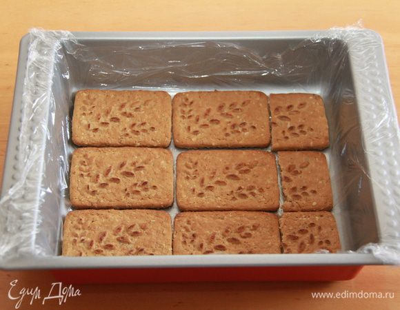 Дно формы выстилаем пищевой плёнкой. Выкладываем нижний слой печенья.