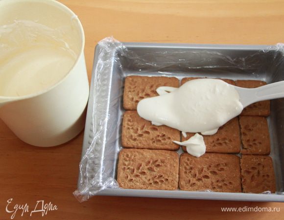Половину молочно-сливочной смеси распределяем по печенью.