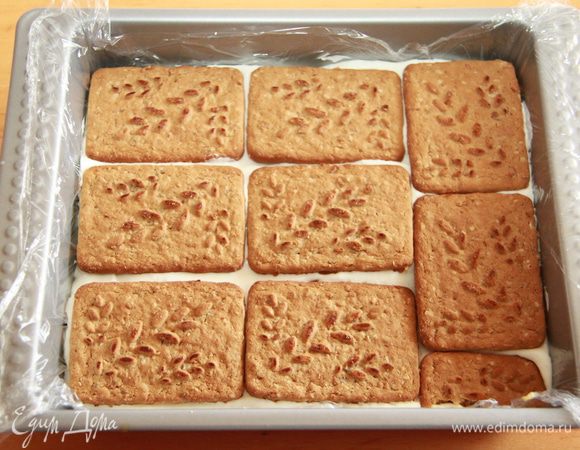 Манго покрываем оставшимся кремом, выкладываем слой печенья. Убираем заготовку в морозилку на полчаса.