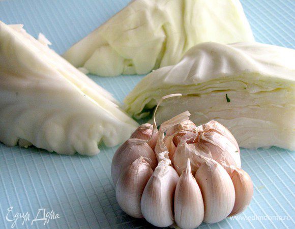 Кочан капусты разрежьте на 8 частей, удалив кочерыжку (я разрезала на более мелкие кусочки). С чеснока снимите верхние слои шелухи, оставив головки цельными.