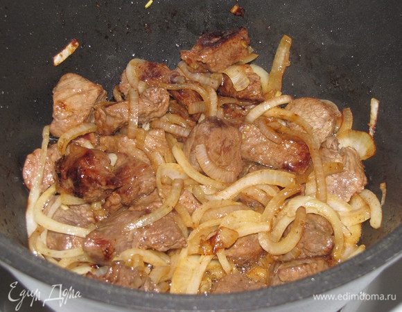 Добавьте к мясу лук и обжарьте, помешивая, до светло-желтого цвета.