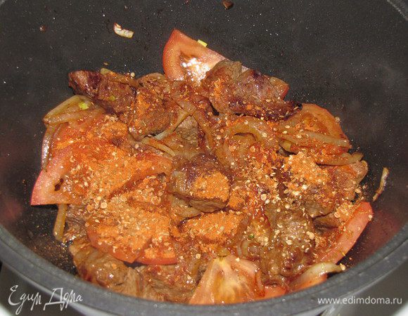 Положите помидоры. Во время их обжарки добавьте смесь специй, убавьте немного огонь. Потушите мясо с луком и помидорами, 5 минут. 