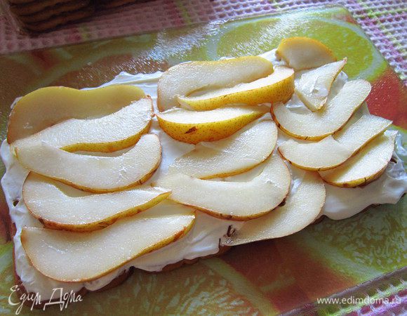 Слой из печенья смазать взбитыми сливками, уложить дольки груш и еще нанести слой сливок.