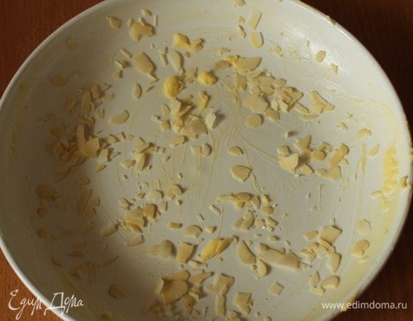 Форму для выпечки смазать сливочным маслом и посыпать миндальными лепестками.