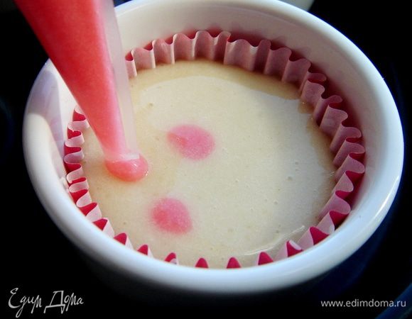 Тестом из кондитерских мешков нанести на кексы "горох" контрастного цвета. Для этого кондитерский мешок на 2-3 мм следует окунуть в тесто кекса и аккуратно выдавить каплю, постепенно вынимая мешок из теста.