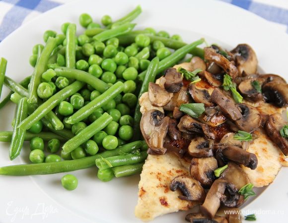 На сковороду верните лук с грибами. Влейте вино, бульон и добавьте еще 1 ст. л. рубленого эстрагона. Доведите до кипения и готовьте 2 минуты. Разложите курицу по тарелкам, сверху — грибной соус. На гарнир у меня были припущенные зеленый горошек и фасоль. Приятного аппетита!