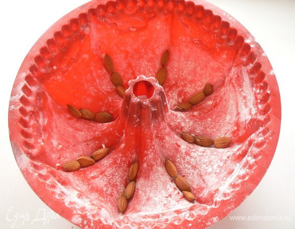 Форму смажьте маслом, посыпьте мукой, выложите миндаль.