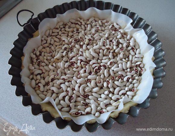 Нагреть духовку до 200 градусов. Форму диаметром 26 см смазать маслом. Тесто раскатать и выложить в форму , сделав бортик. Положить бумагу для выпекания , насыпать горох, можно просто наколоть вилкой тесто , чтобы оно не выгибалось .Выпекать 10 минут. 