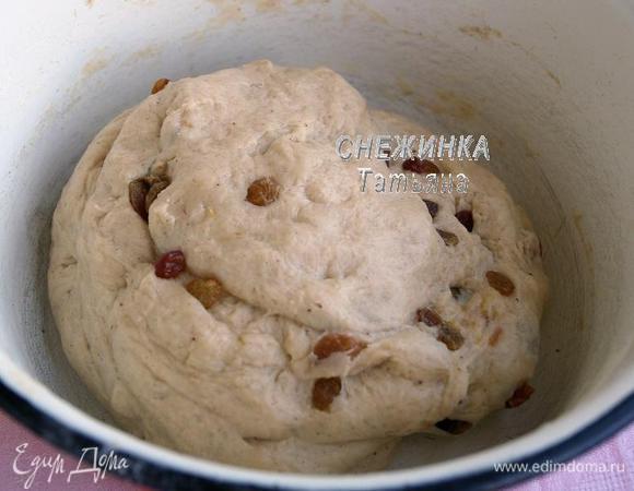 Подошедшее тесто обминаем. Изюм присыпаем небольшим количеством муки и вмешиваем в тесто.