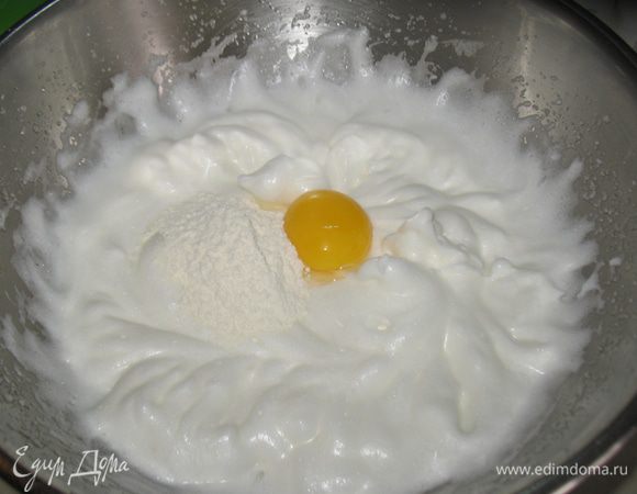 Добавлять по одному желтку и столовой ложке муки с разрыхлителем, аккуратно перемешивая каждый раз. 