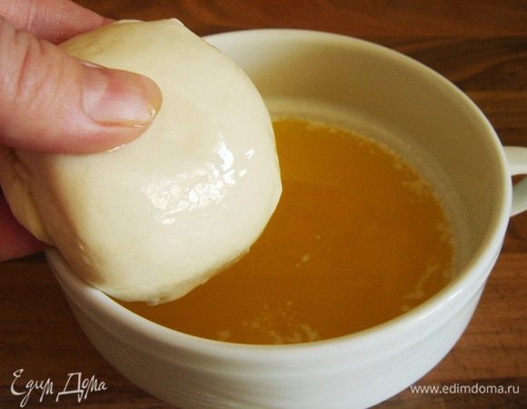 Разогреть духовку до 200 *С. В небольшой миске смешать растительное и сливочное масло. Взять один шарик теста в руку и полностью окунуть его в масло.