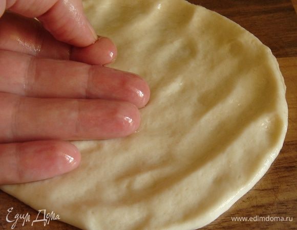 Положить кусок смоченного в масле теста на рабочий стол и размять его пальцами. Затем ладонью и пальцами, слегка нажимая на тесто, разгладить (!) тесто по столу до очень тонкого блинчика. Это очень несложная процедура! Если поверхность блинчика окажется недостаточно масляной, можно смочить пальцы в масле и размазать его по блину.