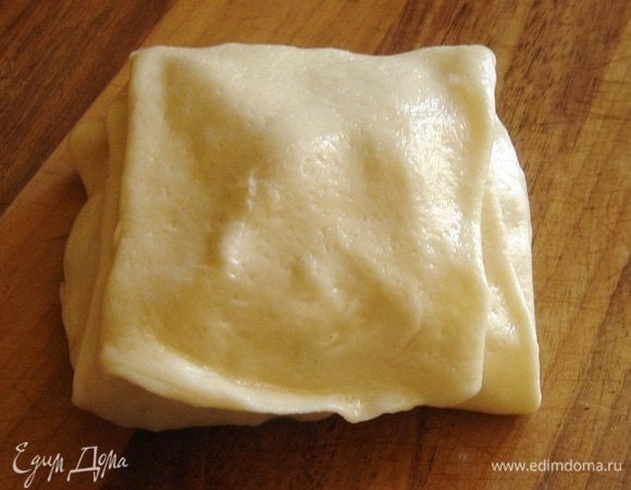 Затем сложить нижний край теста, удаляя воздух из складок теста, и накрыть его верхним краем, опять же чуть смазывая маслом. Немного прижать пирожок ладонью и отложить его в сторону, перевернув швом вниз.