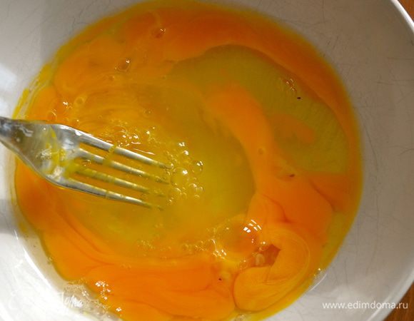 Разбить в миску три яйца и размешать вилкой. Добавить к яйцам половину лука.  