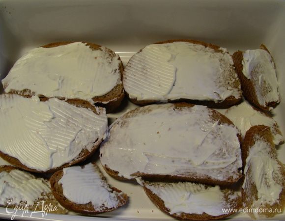 Хлеб смазываем с одной стороны сливочным сыром. В рецепте рекомендуют его разрезать на 4 части. Здесь все зависит от размера Вашей формы и от размера хлеба, который будете использовать. Подходящую форму слегка смазываем маслом и выкладываем туда слой хлеба сыром вверх (половину всего хлеба).
