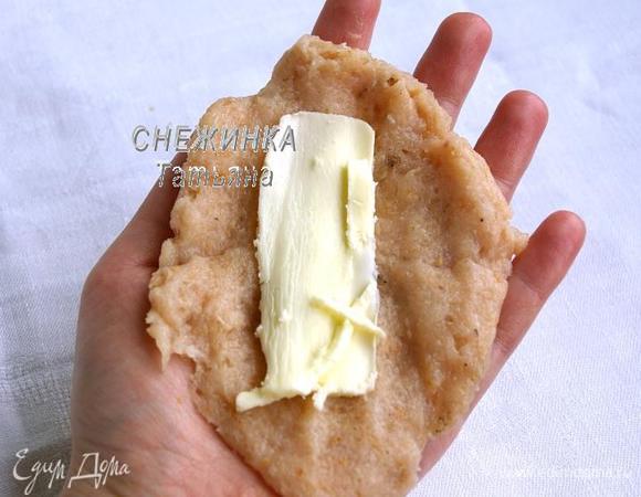 Подготавливаем яйцо для обваливания шницелей, слегка взбив его вилкой. В другую мисочку высыпаем сухарики. Масло разрезаем на 2 брусочка. Берём часть фарша, распределяем его на ладони тонким слоем (фарш достаточно липкий, поэтому время от времени смачивайте ладони в воде). На него кладём кусочек сливочного масла.