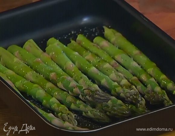 Стебли спаржи, удалив грубую часть, выложить в небольшой глубокий противень, посолить, поперчить, сбрызнуть оливковым маслом, перемешать и отправить в разогретую духовку на 7–10 минут.