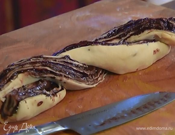 Намазать пласты теста шоколадной начинкой и свернуть в рулеты. Разрезать каждый рулет вдоль пополам и переплести косичкой срезами вверх.