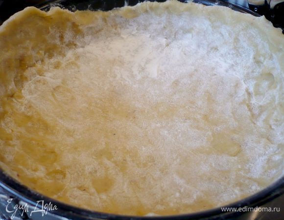 Смазанную сливочным маслом форму выстилаем раскатанным на присыпанной мукой поверхности тестом, образуя достаточно высокие бортики. Накрываем тесто сверху пекарской бумагой и высыпаем наш груз сверху. Ставим в духовку на 12-15 минут.