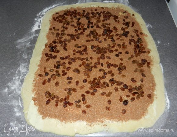 Сверху на масло посыпьте заранее приготовленную смесь для начинки и потом изюм, по желанию.