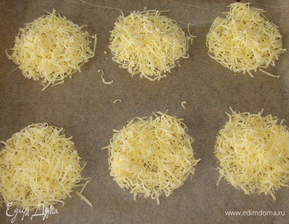 Сыр натереть на мелкой терке, смешать с крахмалом, выложить кругами на противень. Поставить в духовку при температуре 180 градусов.