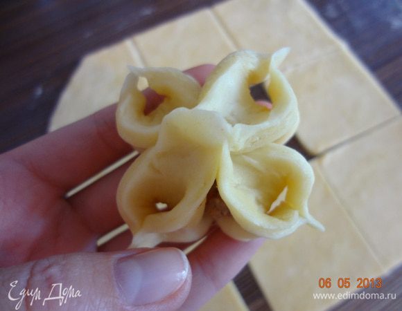 На каждый квадрат положить шарик начинки, защипнуть уголки квадрата в центре, получится конвертик, уголки квадрата вывернуть наружу, получится цветочек.