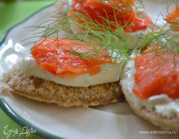 Затем тонкие пластинки семги выложим на приготовленный хлеб со сметаной. Сверху выложим веточки укропа.