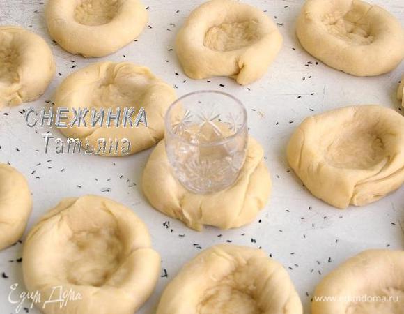 Подошедшее тесто раскатываем в толстый жгут и делим на 13 равных частей. Из каждой части скатываем круглую булочку и укладываем на смазанный маслом противень. Оставляем подняться на 10 минут. Затем с помощью донышка рюмки делаем в каждой булочке углубление в центре. Если тесто будет прилипать, можно немного смазать его в масле.