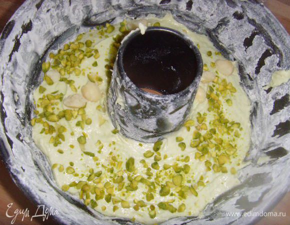 Форму для кекса смазать маслом и посыпать мукой. Выложить половину теста , посыпать колотыми орешками и оставшимся тестом. Разровнять поверхность теста лопаточкой.