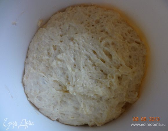 Через 45 минут подошедшее тесто обмять, выложить на рабочую поверхность, присыпанную мукой, вымесить и разделить на две неравные части.