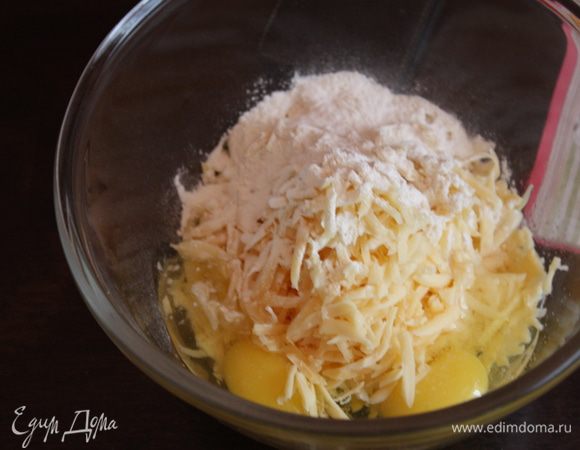 Пока тесто у нас подходит, сделаем начинку. Натрем сыр на крупной терке, сложим в миску, к нему добавим яйца, муку с разрыхлителем и соль. Все перемешаем.