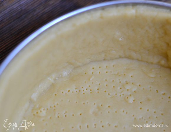 Достаем наше охлажденное тесто из холодильника. 1.Вариант - раскатать тесто на поверхности,обязательно присыпанной мукой,а потом вырезать круг,с размером формы,а затем вырезать полоски,с размером бортиков. 2 Вариант-разделить тесто на 2 части,одну часть теста раскатываем в круг с диаметром нашей формы,на присыпанной мукой поверхности,другую часть раскатываем в полоску,с размером бортиков нашей формы,аккуратно ножом выравниваем и перемещаем в форму,застеленную пергаментом. Сначала стелим низ,руками выравниваем,затем аккуратно стелим бока и руками все подправляем. И 3 Вариант-тесто раскатать полностью и скалкой выстелить в форму,но оно такое хрупкое и ломкое,что мне было сделать так трудновато и я делала как в 1 варианте. Стараться раскатать тесто потоньше, ну конечно,чтоб не просвечивалось.Наколоть тесто вилкой и поставить в холодильник на минут 30.