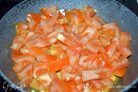 В сковороде,которую потом можно будет поставить в духовку,разогреть столовую ложку масла.Ожарить в нем измельченный чеснок и нарезанные помидоры.