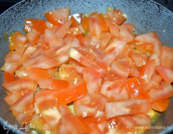 В сковороде,которую потом можно будет поставить в духовку,разогреть столовую ложку масла.Ожарить в нем измельченный чеснок и нарезанные помидоры.