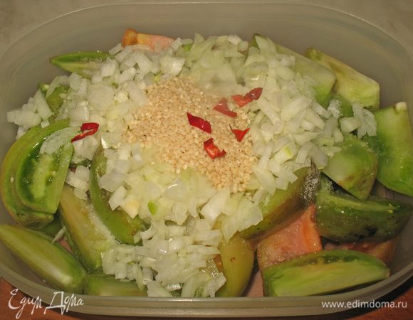 Помидоры кладем в контейнер в котором они будут мариноваться. К ним добавляем лук, кунжут и солим. Посолить надо немного сильнее чем обычно солим  салат. 