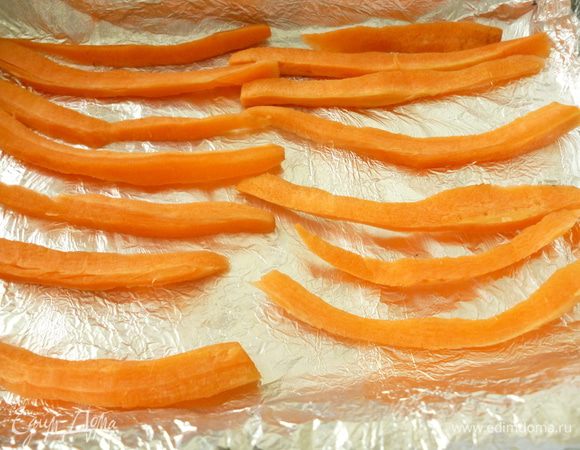 В форму для запекания выложите двойной слой пергамента или фольги. Затем — брусочки очищенной моркови, чтобы курица не подгорала и кожа не прилипала ко дну во время запекания. Сверху расположите курицу.