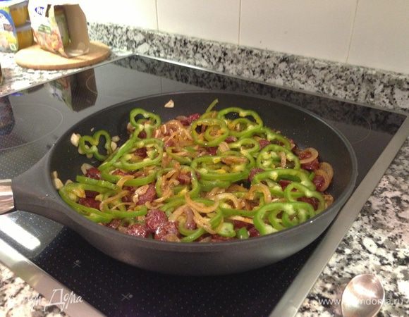 Колбаску чоризо порезать на дольки 0,5 см. Сладкий перец - тонкими кольцами. Все добавить к луку и чесноку. Готовить еще 3-4 минуты. Если вы не нашли чоризо, его, на мой взгляд, можно заменить грудинкой или беконом.