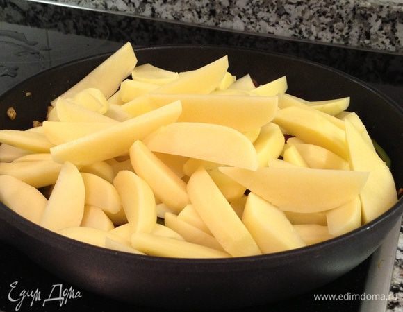 Картофель очистить. Порезать на дольки.  Выложить в сковороду. Посолить, поперчить. Добавить вино и воду и тушить на медленном огне (так, чтобы слегка кипело) 10-15 минут, пока жидкость слегка не выпарится, а картофель не станет " прозрачным", мягким (готовым на 2/3)


