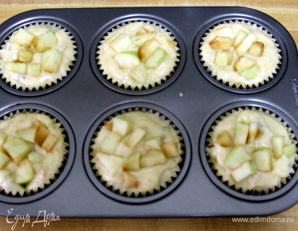 Раскладываем приготовленное тесто в формы для маффинов и сверху кладем оставшиеся яблоки.