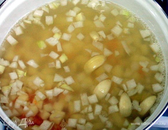 В кастрюлю наливаем воду (или бульон), кладем чечевицу, лук (мелко нарезанный), картофель (нарезанный на небольшие кубики) и чеснок (целыми зубчиками). Закрываем крышкой и доводим до кипения. Затем немного убавляем огонь и варим 15-20 минут, до готовности чечевицы и овощей.