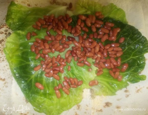 на листья капусты выложить фасоль, предварительно освобождённую от жидкости