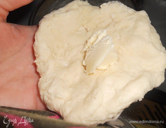 Когда пройдет два часа, тесто хорошо подойдет и станет мягкое, теперь его нужно обмять, и отщипывать по небольшому кусочку, кусочек размять в лепешку и в серединку положить 1 ч. л. охлажденного сливочного масла, защипнуть края и сформировать булочку.