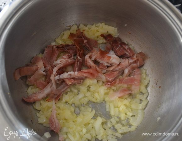 Как только лук слегка посветлеет, добавить к нему нарезанную полосками грудинку. 